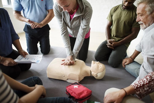 People performing CPR on a dummy in a CPR certification class.