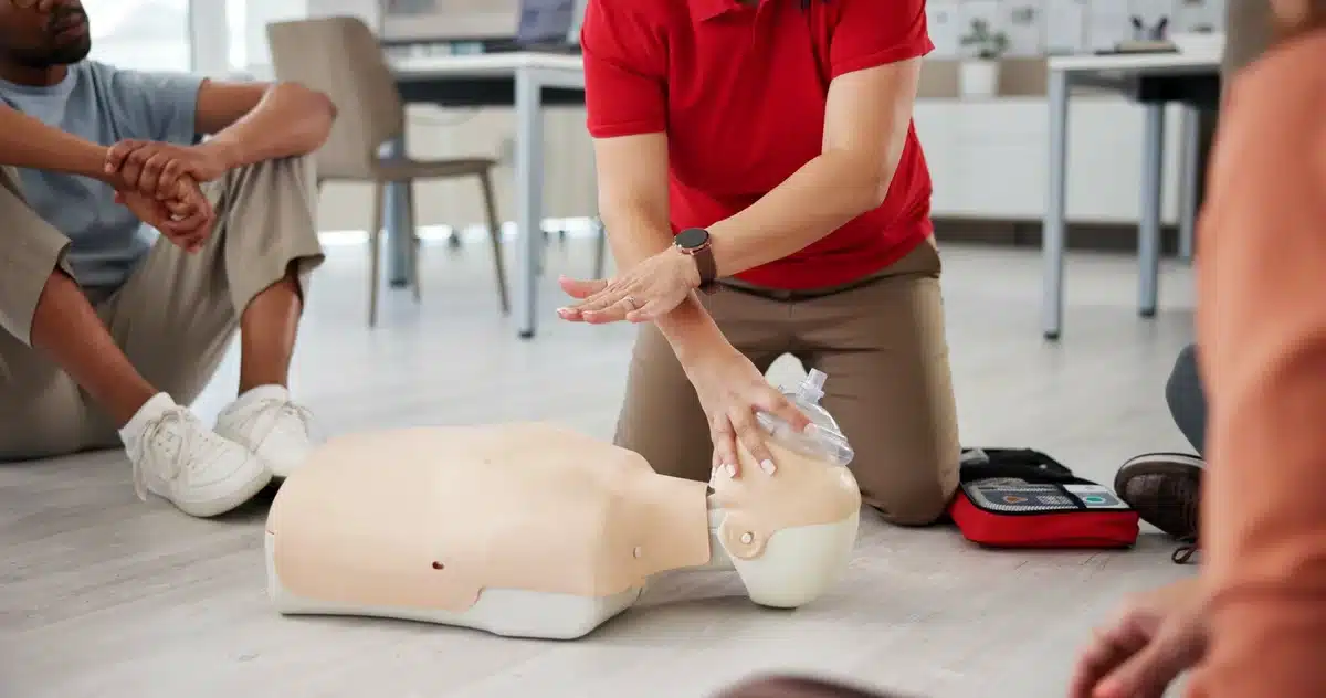 An instructor showing how to perform CPR on a dummy.