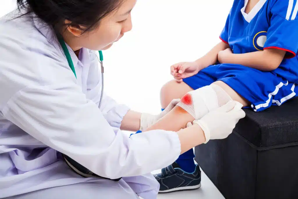Woman applying bandage to child's leg.