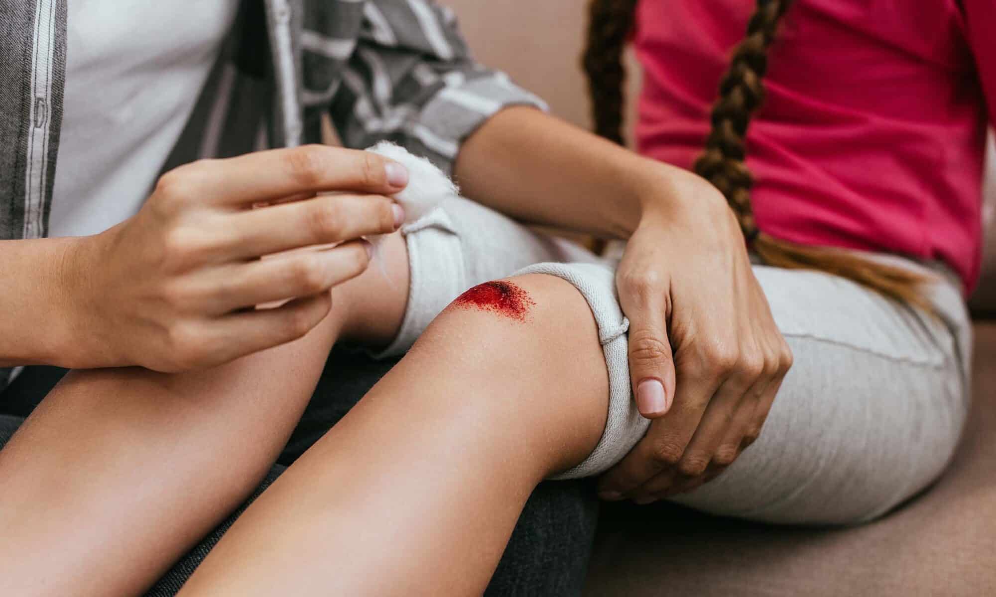 Woman treating minor cut on girls knee